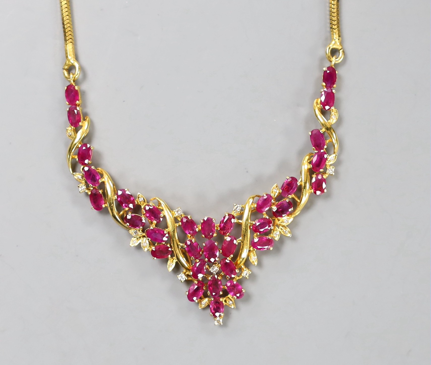 A modern Thai yellow metal, oval cut ruby and diamond chip cluster set necklace, 40cm, gross 22.6 grams.
